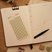 Transparent fern green heart planner sticker sheet with 120 miniature matte stickers displayed on an open weekly planner beside black tweezers, showing the product ready for planning and journaling.