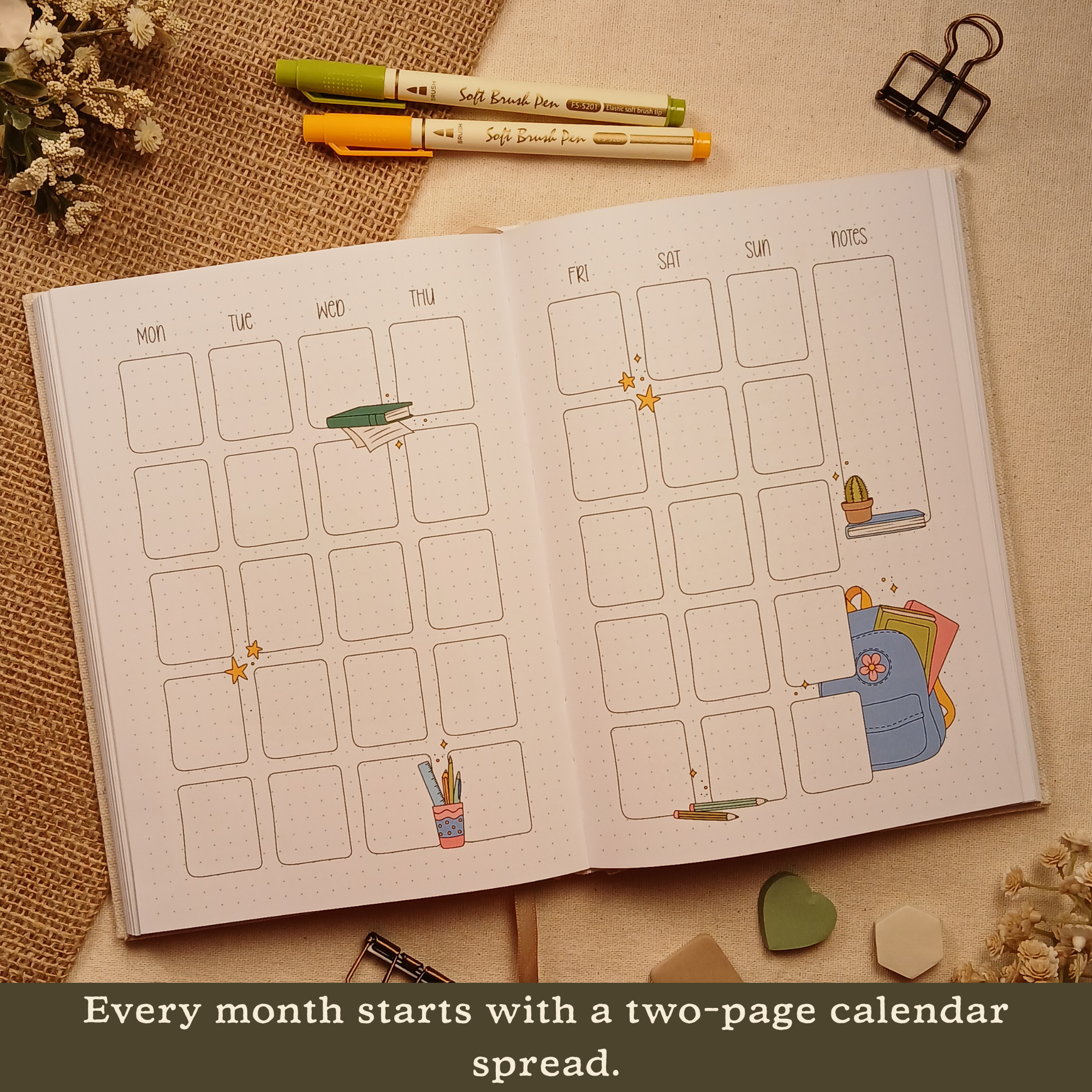 Open Booked Journal displaying a two-page monthly calendar spread with colorful book-themed illustrations and room for planning. Text on image: 