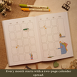 Open Booked Journal displaying a two-page monthly calendar spread with colorful book-themed illustrations and room for planning. Text on image: 
