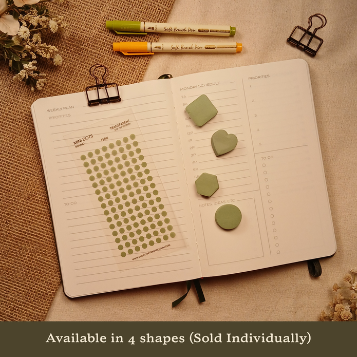 Fern green transparent matte round planner dot stickers displayed with coordinating heart, circle, square, and hexagon sticky notes on an open planner. The image includes the text, 