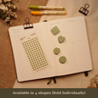 Fern green transparent matte round planner dot stickers displayed with coordinating heart, circle, square, and hexagon sticky notes on an open planner. The image includes the text, 
