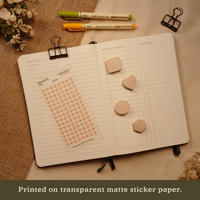 Blush pink transparent heart planner sticker sheet displayed with coordinating sticky notes on an open planner. Text reads: 