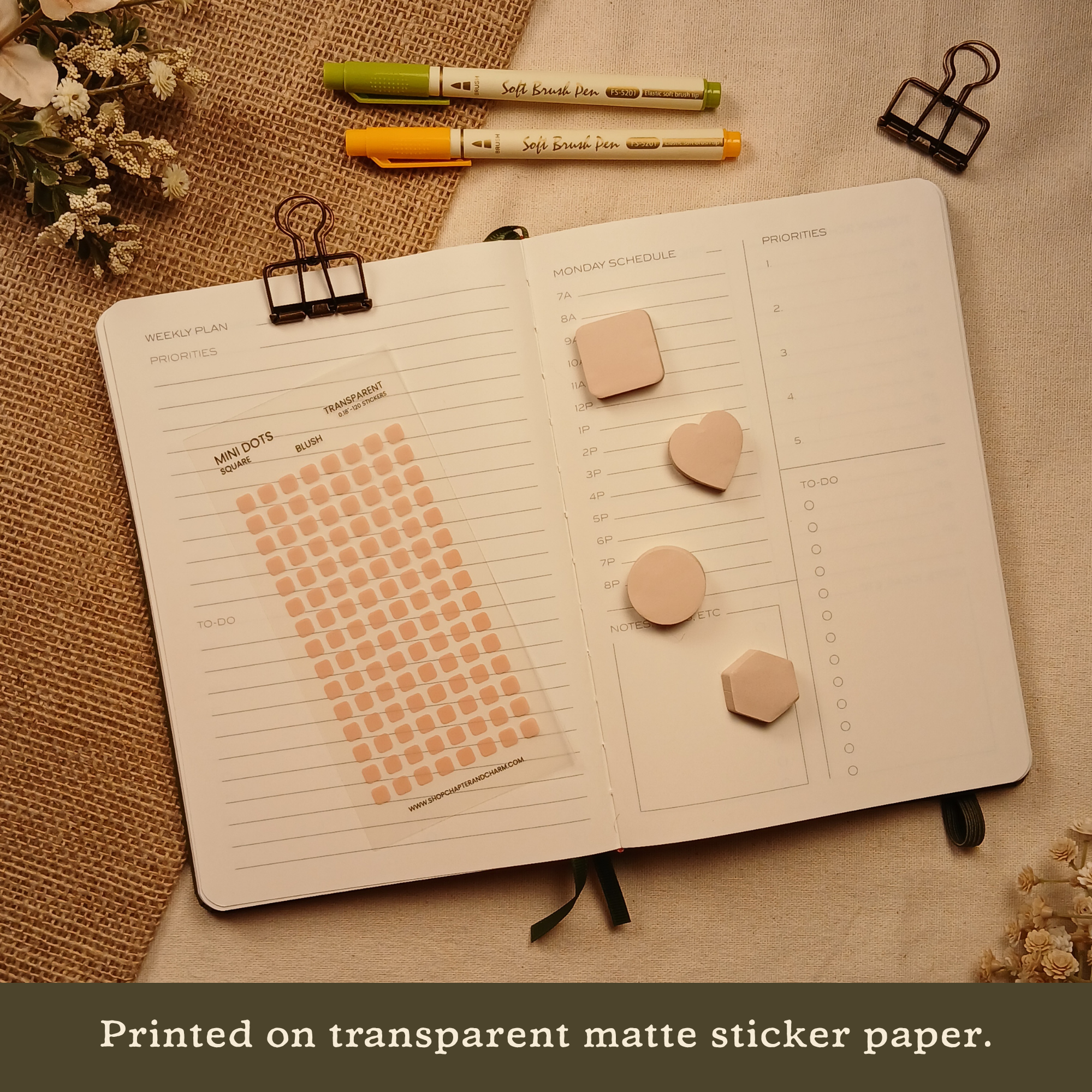 Blush pink transparent matte square planner stickers displayed with coordinating sticky notes on an open planner. The image includes the text, 