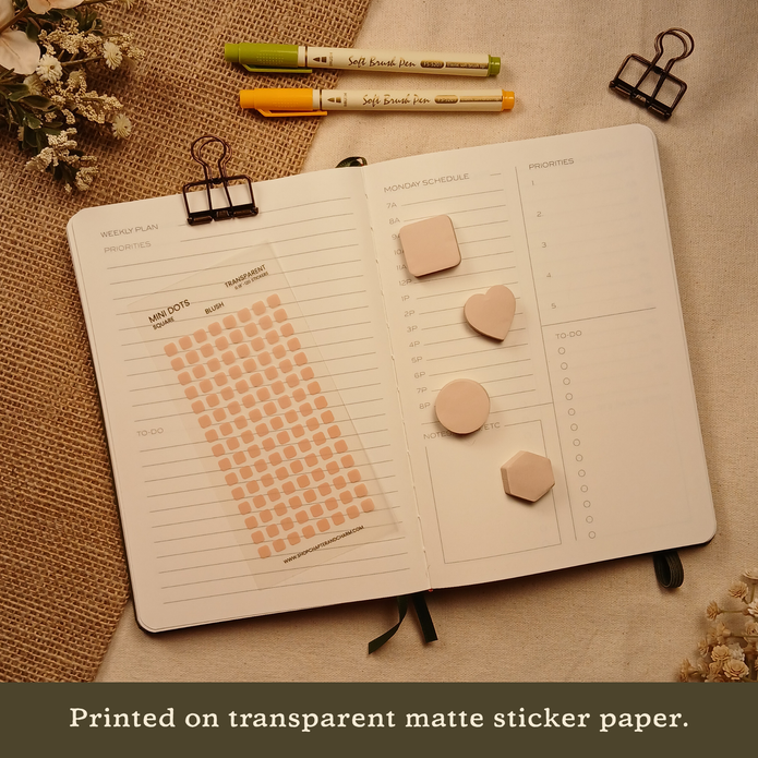 Blush pink transparent matte square planner stickers displayed with coordinating sticky notes on an open planner. The image includes the text, 