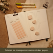 Blush pink transparent matte square planner stickers displayed with coordinating sticky notes on an open planner. The image includes the text, 