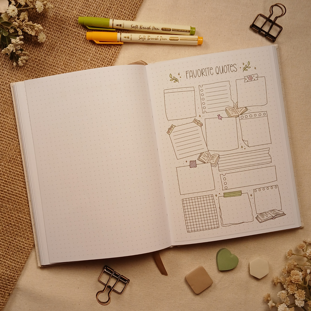 Open A5 dotted journal featuring a color Favorite Quotes stick-in page with decorative note boxes, books, washi tape accents, and stationery-inspired illustrations for recording meaningful quotes and favorite passages. Styled with brush pens, binder clips, dried florals, burlap, and neutral sticky notes.