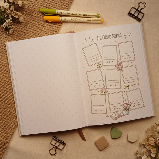 Open A5 dotted journal featuring the Favorite Songs stick-in page with soft earth-tone floral accents and decorative music notes. Nine music-themed cards provide space to record meaningful songs, favorite artists, albums, or playlists while adding a cozy, creative touch to any journal spread.