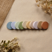 Stack of round sticky notes arranged to showcase all ten Chapter & Charm color options on a neutral linen background with dried florals.